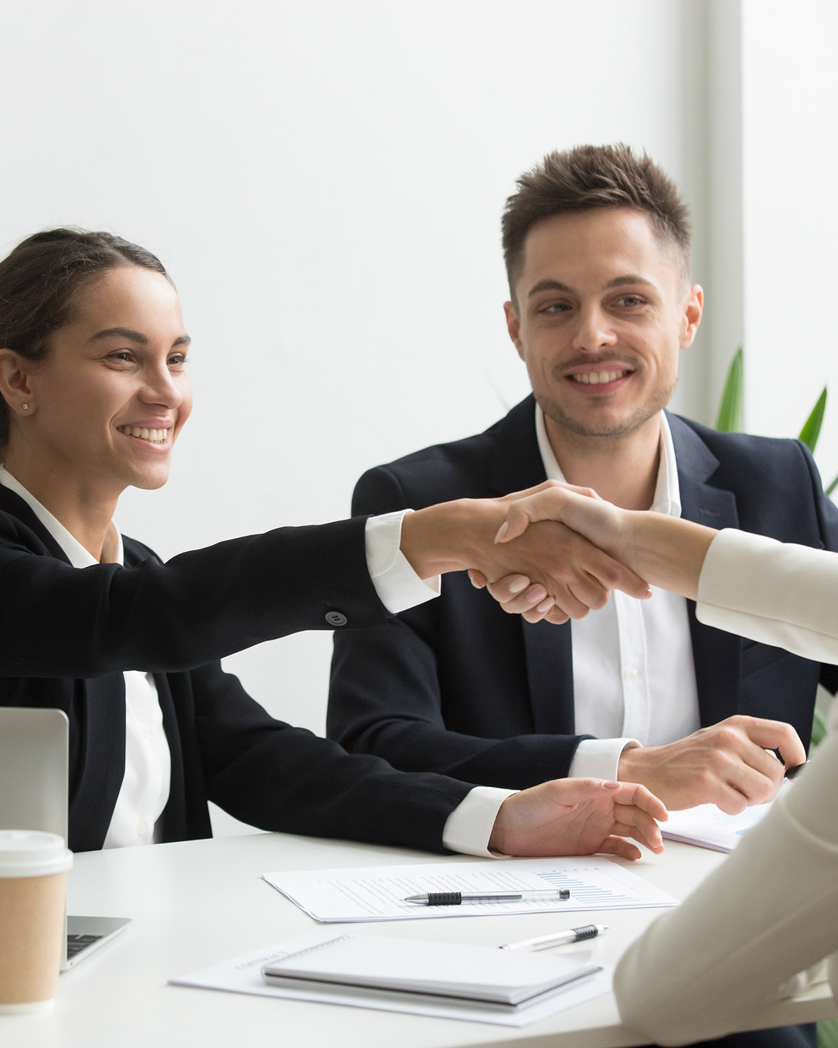 Smiling HR managers greeting female job applicant with handshake during recruiting or interview. Businesswoman making good first impression shaking hands of business partners. Partnership, cooperation